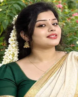 Kavya in a cream saree and dark green blouse among flowering garden plants