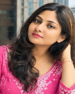 Sneha in a pink chikankari kurta with city buildings behind her