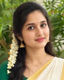 Pooja in a cream saree with a green border, jasmine woven into her braid