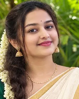 Nisha in a cream kasavu saree with gold earrings and a small bindi