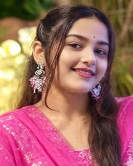 Nisha in a pink dupatta and silver jhumkas, warm fairy lights behind